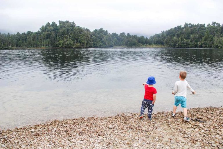 Kids throwing stones at Lake Kaniere, a short walk on the West Coast, New Zealand I Backyard Travel Family