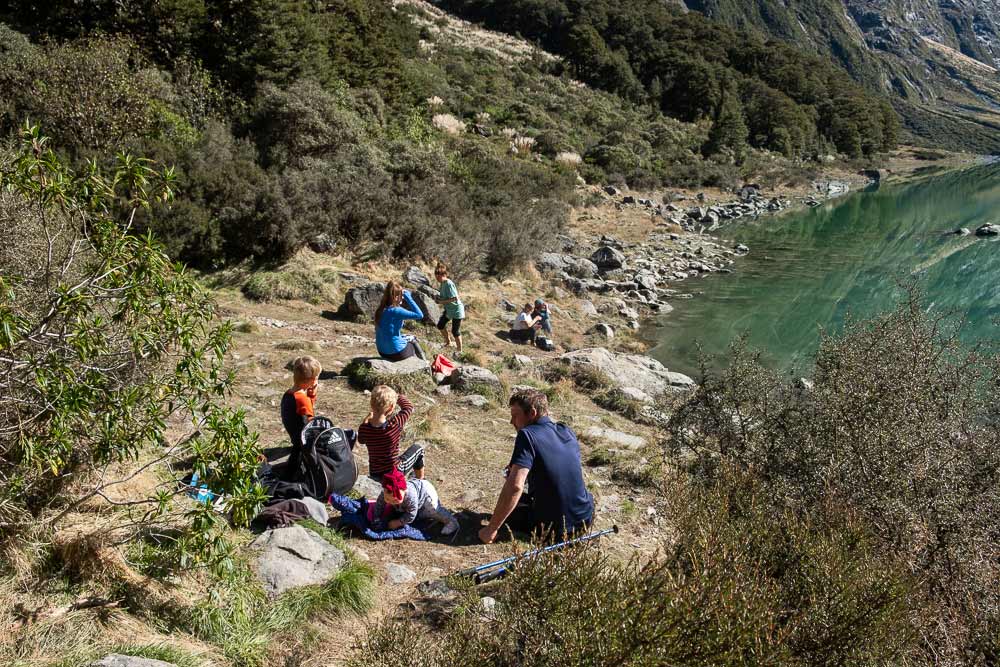 Sitting beside the beautiful Lake Marian, on the Lake Marian track, a great half way walk on the Milford Road Highway, Fiordland. You can even walk to Lake Marian with kids by Backyard Travel Family