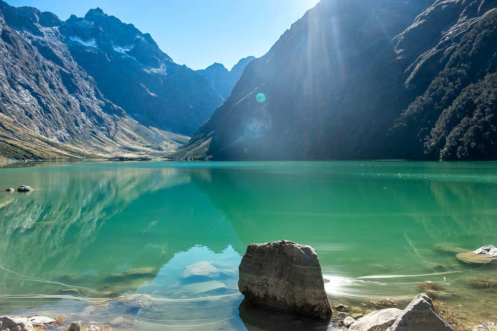 See this beautiful alpine lake on Lake Marian track, a great half way walk on the Milford Road Highway, Fiordland. You can even walk to Lake Marian with kids by Backyard Travel Family