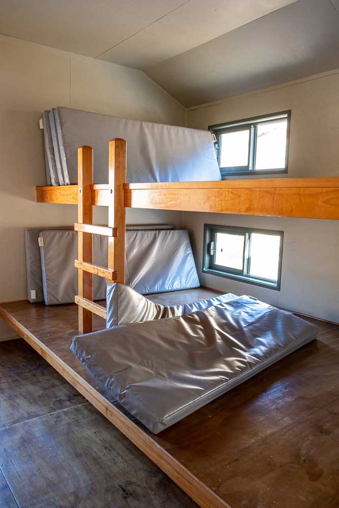 Bunk beds at Woolshed Creek Hut, Mt Somers Track. They are shared bunks with multiple mattresses lying side by side. Photo by Backyard Travel Family, New Zealand