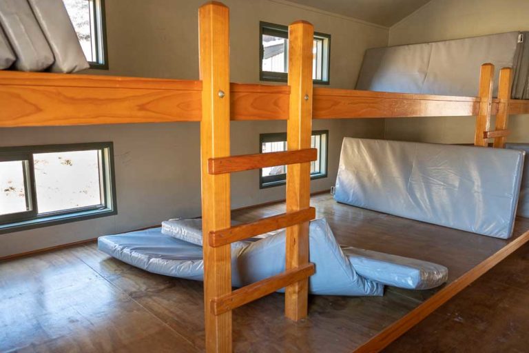 Close up of Bunk beds at Woolshed Creek Hut, Mt Somers Track. They are shared bunks with multiple mattresses lying side by side. Photo by Backyard Travel Family, New Zealand