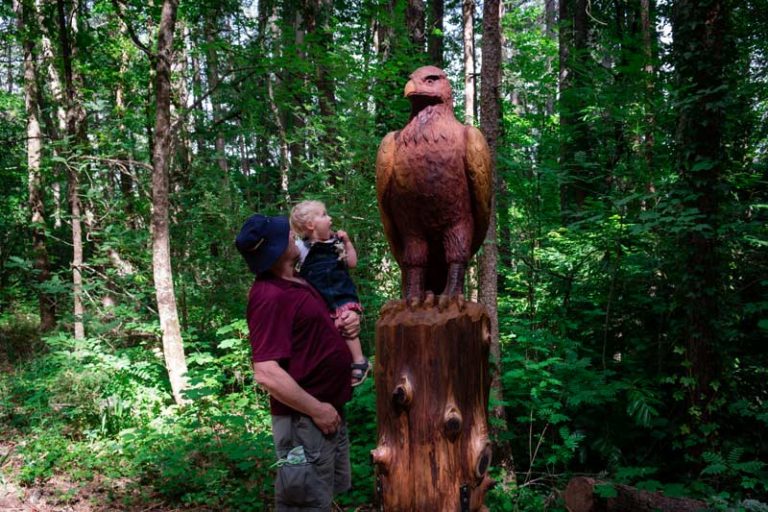 Grandad and Emilia from Backyard Travel Family check out the beautiful wooden eagle sculpture on the Forest Amble Walk