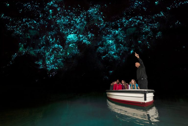 Tourists listening to a guide in the boat at the Glow Worms tour at Waitomo Caves