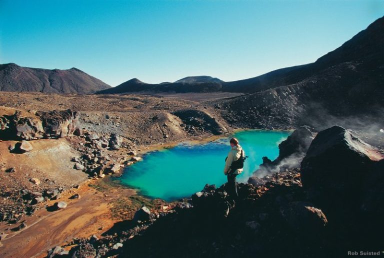 Tourist looks over at the Emerald Pools down below on the Tongariro Crossing hike; one of the best hikes in New Zealand's North Island