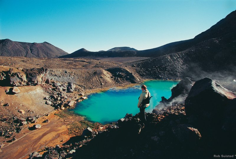 Tourist looks over at the Emerald Pools down below on the Tongariro Crossing hike; one of the best hikes in New Zealand's North Island