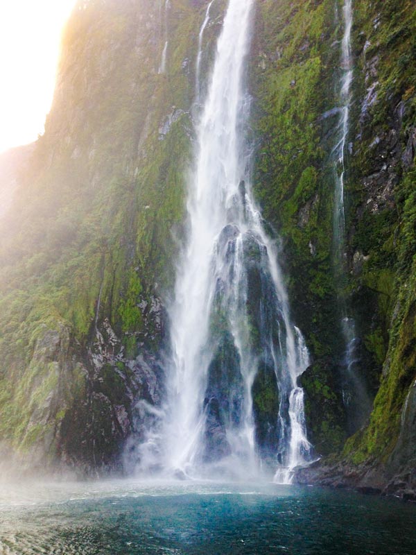 Powerful waterfall spills into the fjord on the Milford Sound Cruise