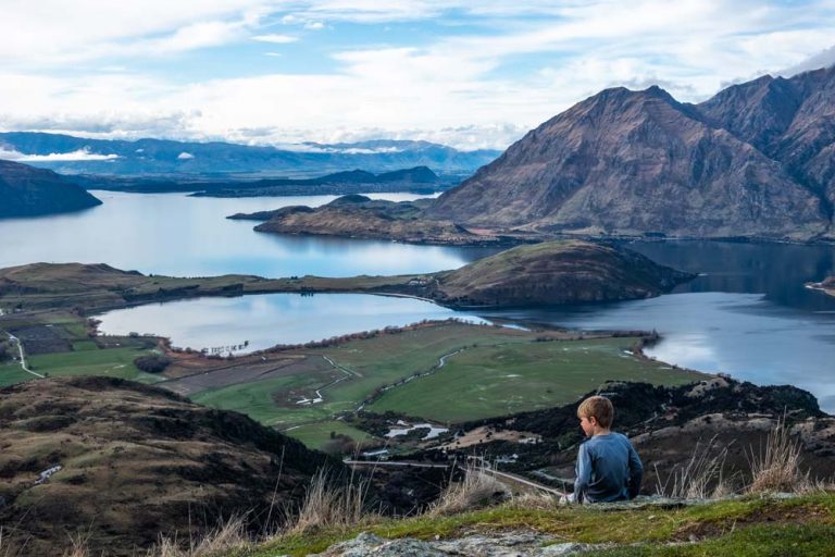 Nathan from Backyard Travel Family sits an looks over the view over Lake Wanaka from the Rocky Mountain wanaka track