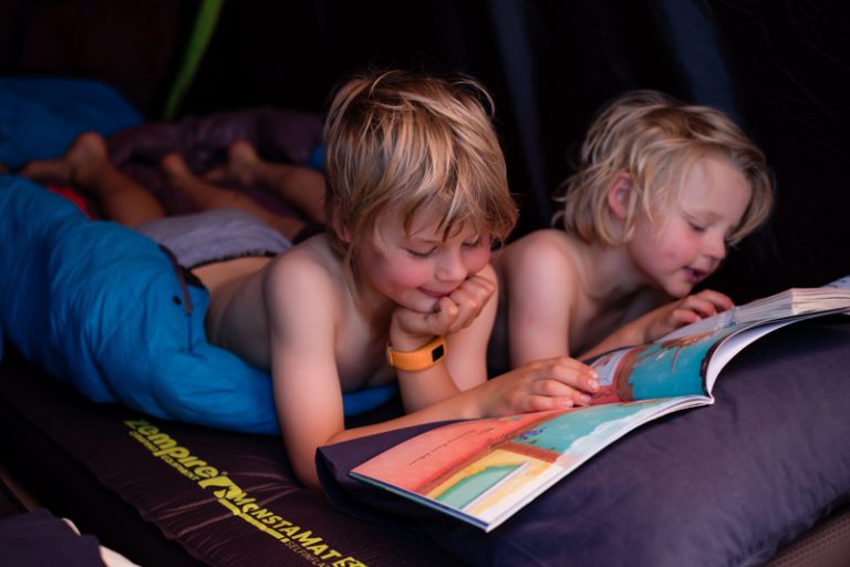 Nathan and Kipton from Backyard Travel Family lie on their Monstamat camping mat before bed
