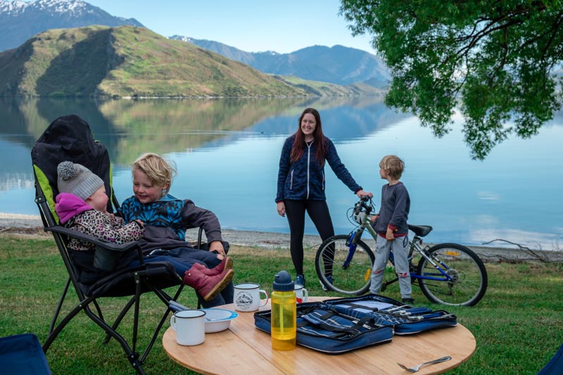 Family sit on their camping chairs overlooking Lake Wanaka