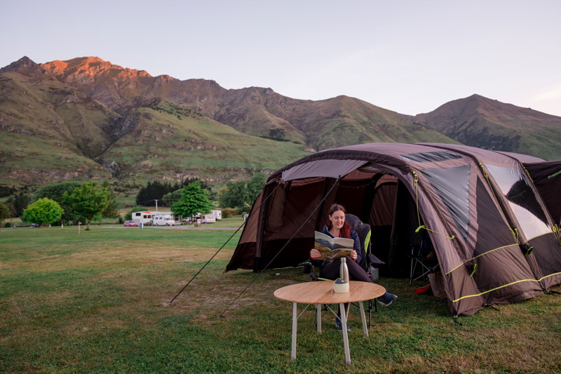Jennifer from Backyard Travel Family sits outside Zempire tent at sunset in Glendhu Bay Wanaka