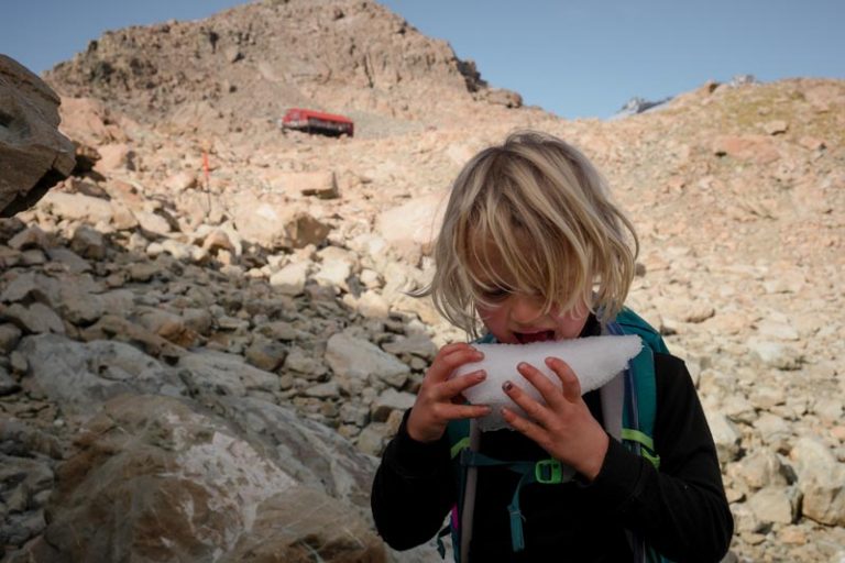 Kipton eating ice with the red Mueller Hut in the backyground