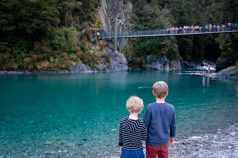 2 boys look up at the people jumping off the bridge at Blue Pools Wanaka New Zealand