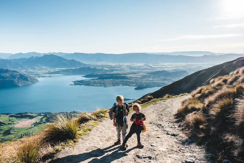 Kids hike up Roys Peak on a sunny summers day, overlooking Lake Wanaka NZ