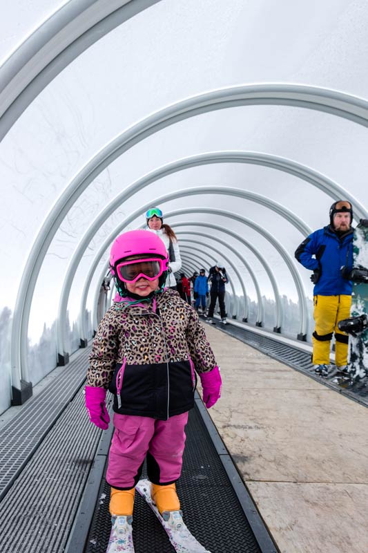 First time Skiing in Queenstown, Emilia from Backyard Travel Family stands on the magic carpet in the snow dome at the Remarkables NZ