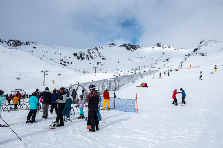 People standing in line waiting for the dual magic carpet conveyor for the beginner slopes at the Remarkables Ski field, Queenstown, New Zealand