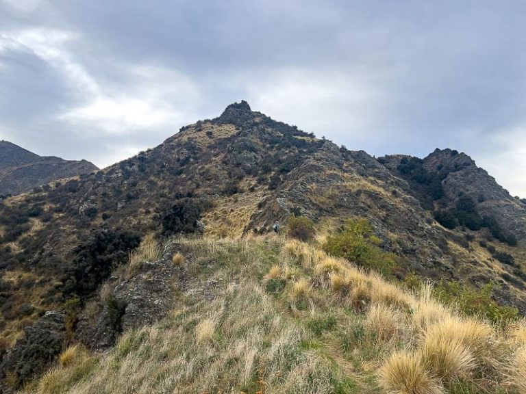 Spot a small child who looks tiny in comparison with the huge mountain on the ridgeline part of the Breast Hill Track at Lake Hawea Wanaka
