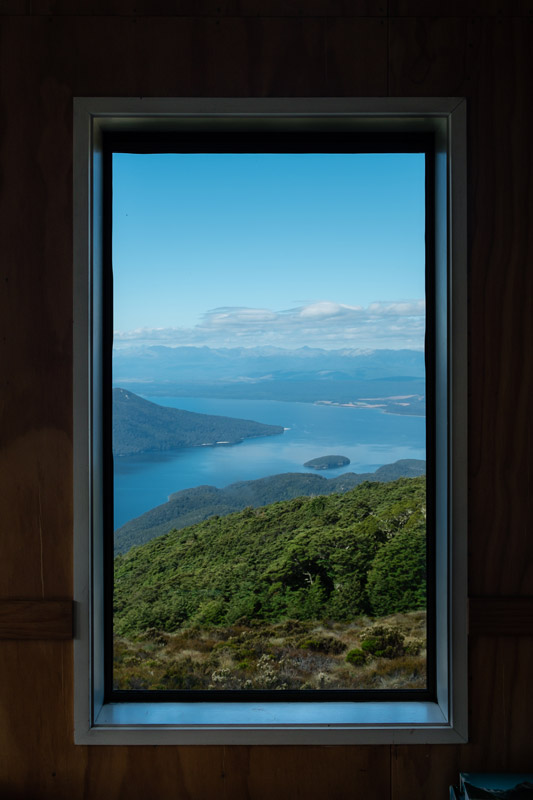Beautiful view of Lake Te Anau and the green native bush from a window at Luxmore Hut on the Kepler Track