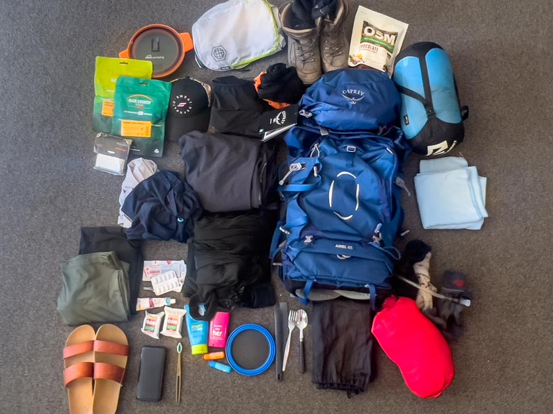 Flat lay of what adults took on the Kepler Track including tramping pack, sleeping bag, clothing, cooking equipment and tramping accessories