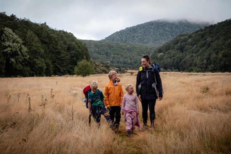 Mother and three kids walk in the clearing close to Kiwi Burn Hut
