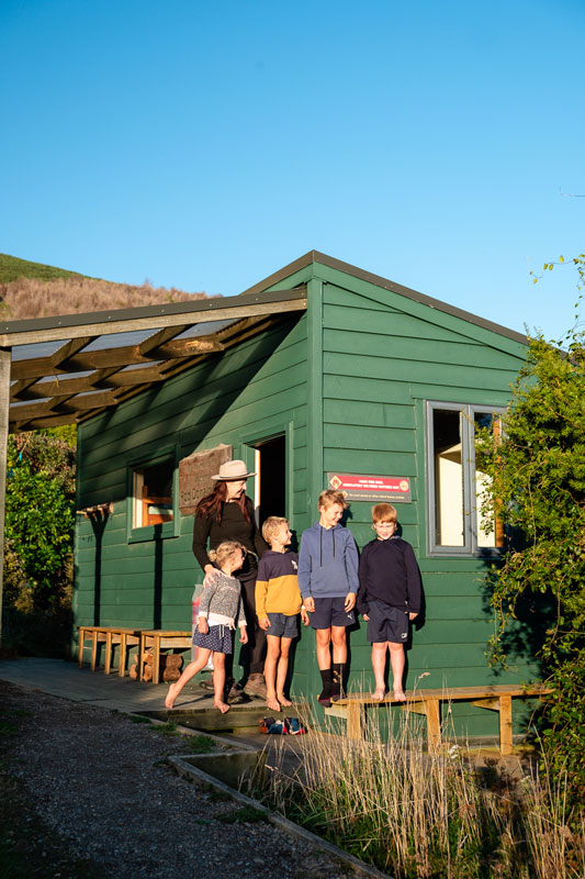 Backyard Travel Family stand outside the green Rod Donald Hut